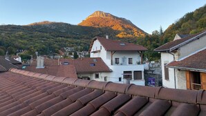 Ein Wohngebiet mit terrakottafarbenen Dächern, weißen Häusern und einem Berg im Hintergrund.