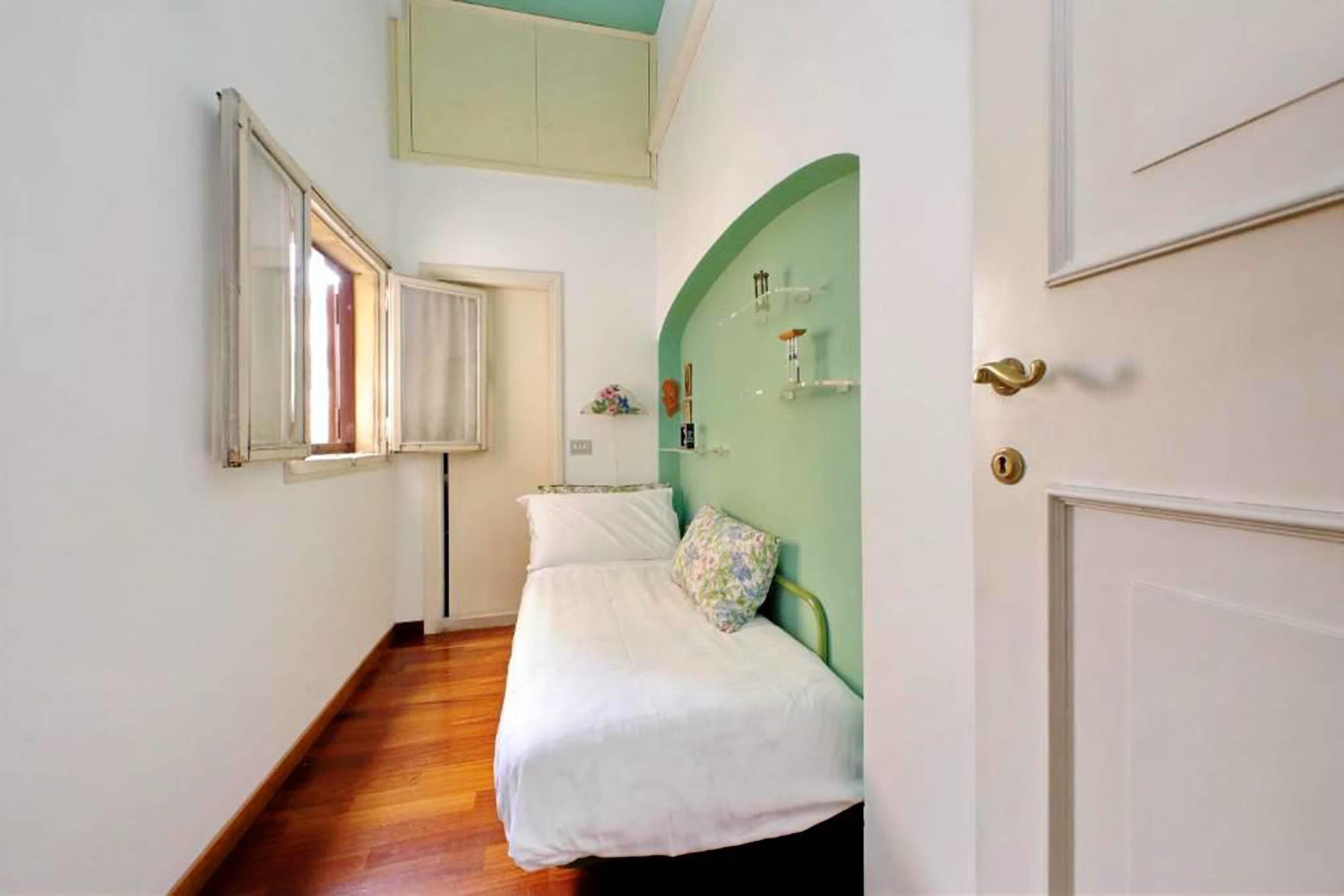 Une petite pièce avec un lit, une fenêtre et une porte.