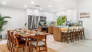 A modern kitchen with white cabinets, stainless steel appliances, and a central island with bar stools. - Oasis On Arroyo - 3 bed, 2 bath, separate office (Palm Springs)