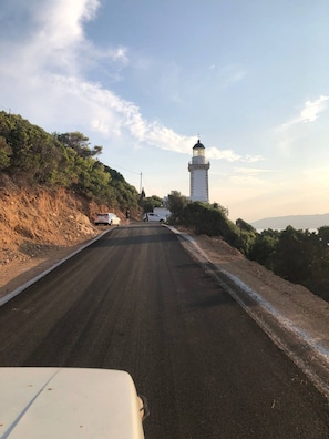 Uma estrada que leva a um farol sob um céu claro.