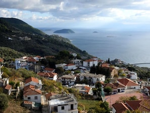 Uma vila costeira com casas em terraços, vista para o mar e paisagem montanhosa.