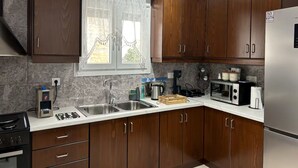 Una cucina moderna con mobili in legno, un frigorifero in acciaio inossidabile, un forno a microonde e un piano cottura a gas.