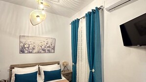 Una camera da letto con un letto, una televisione, una luce a soffitto e tende.