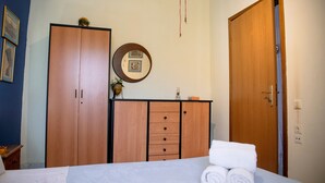 Un dormitorio con cama, armario de madera, espejo y puerta.