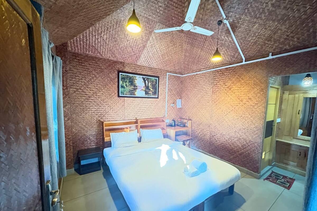 A bedroom with a bed, a ceiling fan, and a wall-mounted TV.