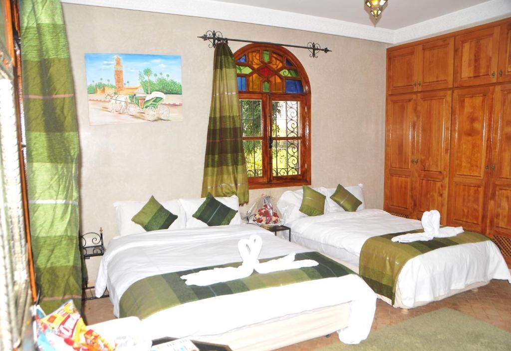 Una camera d'albergo con due letti, una finestra con un decoro in vetro colorato e un armadio in legno.