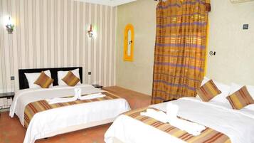 A hotel room with two beds, striped wallpaper, a curtain, and a wall-mounted light fixture.