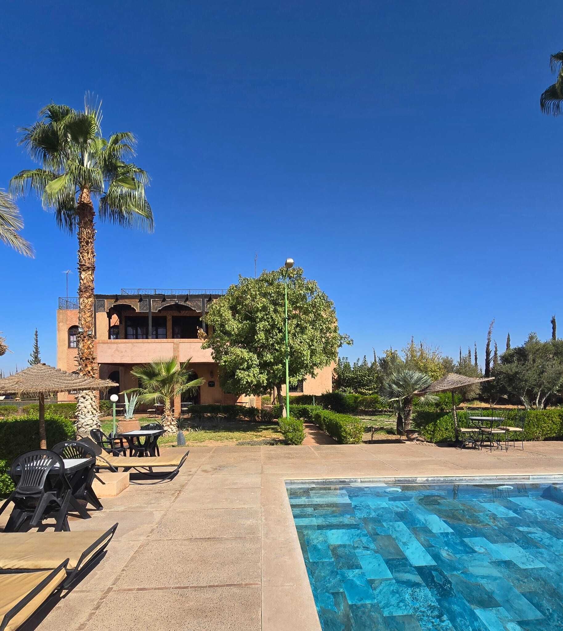 A pool area with lounge chairs and a building with a balcony in the background.