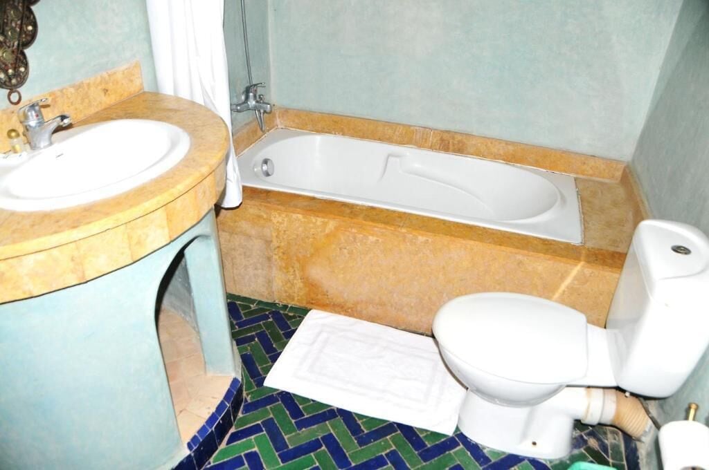 A bathroom with a sink, bathtub, toilet, and a patterned floor.