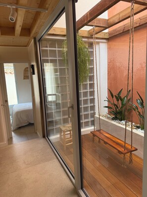 A room with a sliding glass door leading to a wooden deck with a swing chair and plants. - Exceptional property, 3 suites—50 m from the beach. Entire property: Villa Hyères, France (Hyères)