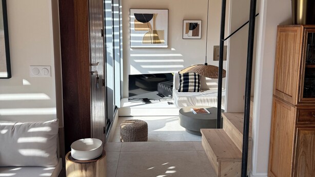 Een modern interieur met een houten plafond, een bank, een bijzettafeltje en een kast.
