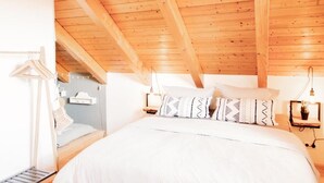 A bedroom with a wooden ceiling, a bed with patterned pillows, a bedside table with a lamp, and a hanging light fixture. - Sohana Lifestyle Apartment Stefan's Home (Rust)