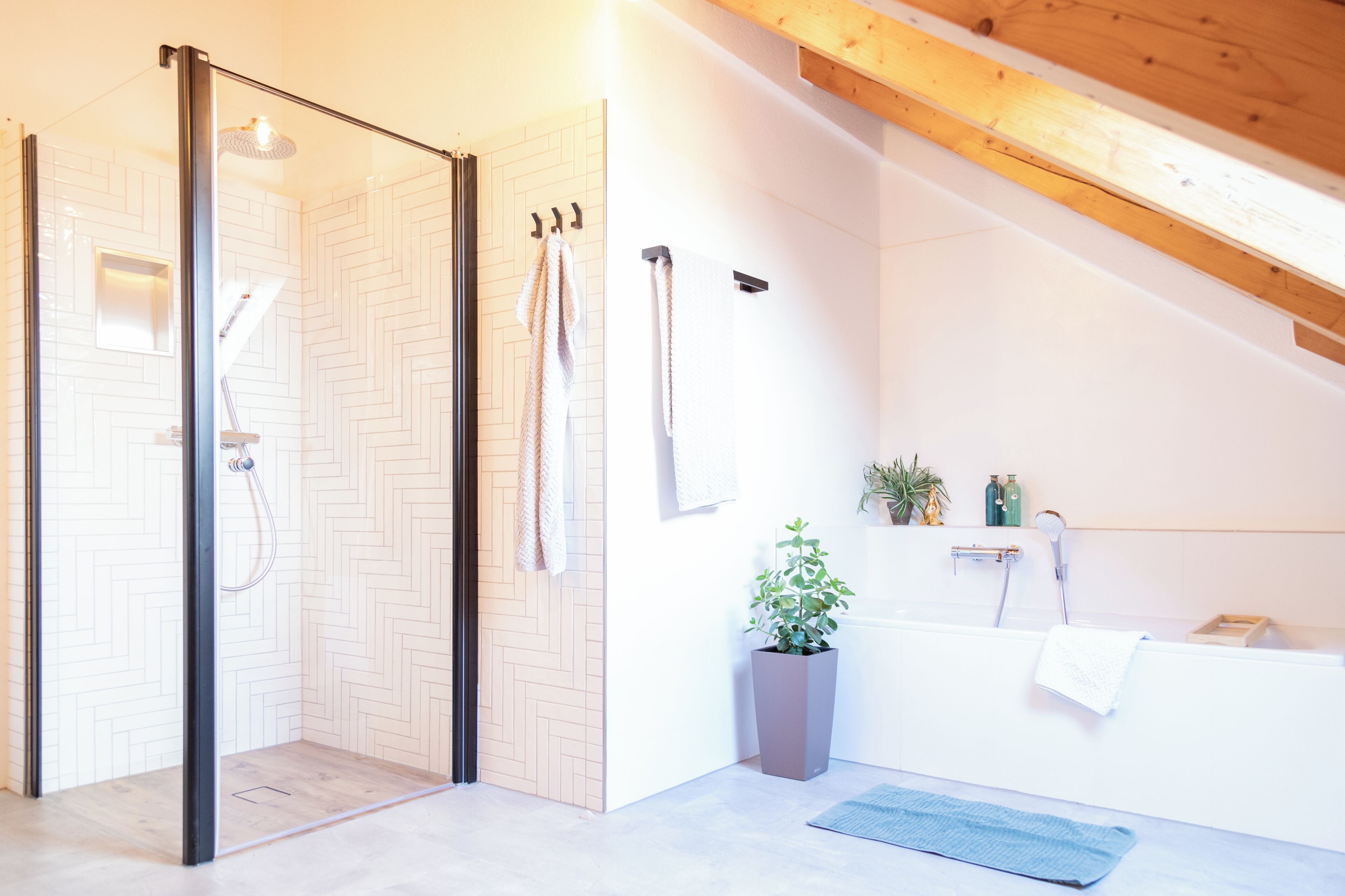 Un baño moderno con mampara de vidrio, bañera y una planta en maceta.