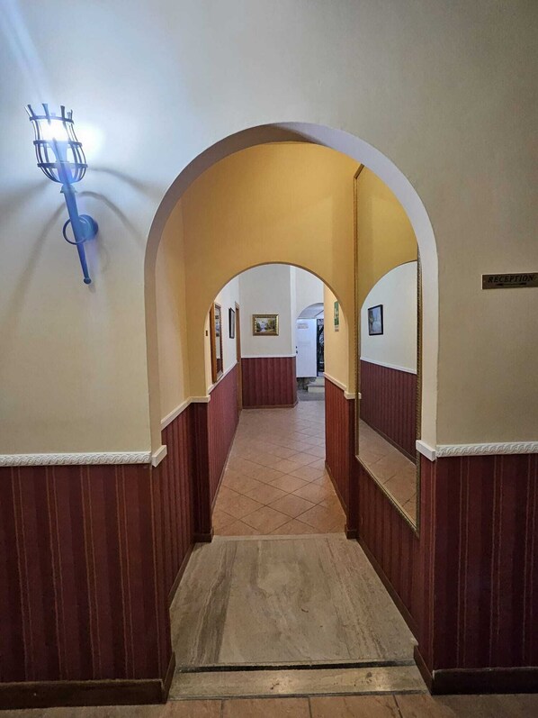A hallway with a reception area at the end, featuring a tiled floor and wooden paneling on the walls. - Hotel Giubileo (Rome)