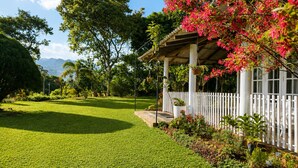 A well-maintained lawn, a white fence, and a gazebo with hanging plants. - Aura Hilltop Matale (Matale)