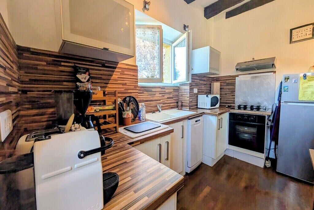 A compact kitchen with a wood-patterned backsplash, a built-in microwave, a sink, a stove, and a refrigerator.