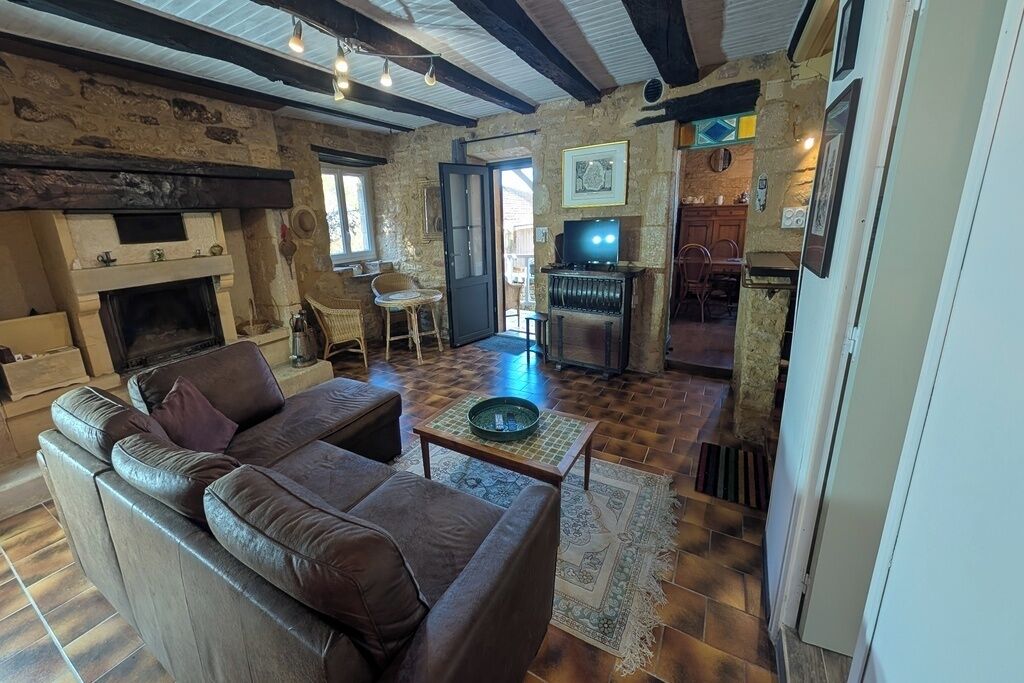 Una sala de estar acogedora con chimenea, un sofá, un televisor y una zona de comedor.