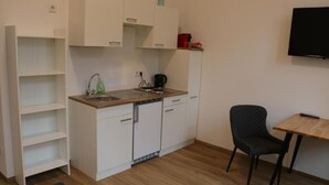 A compact kitchenette with a sink, a coffee maker, and a chair. - RiverView Apartments (Linz)