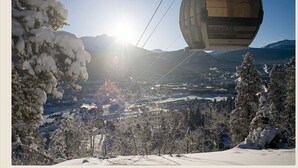 A cable car moving over a snowy landscape with mountains in the background. - Grand Timber Lodge Studio, Hot Tubs, Pools & Sauna, map location is not correct (Breckenridge)