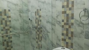Kylpyhuone, jossa on lasiseinällä varustettu suihku, wc ja pesuallas.