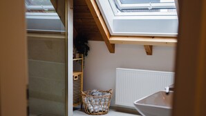 A skylight in a room with a white radiator, a wicker basket, and a small rug. - Sohana House (Rust)