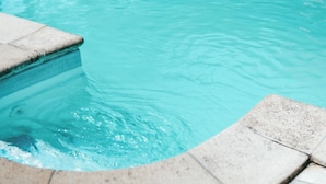 A swimming pool with a stone edge and a tiled deck. - Sohana House (Rust)