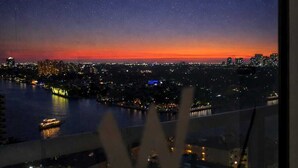 Une vue nocturne d’une ville, avec la lune visible et une rivière.