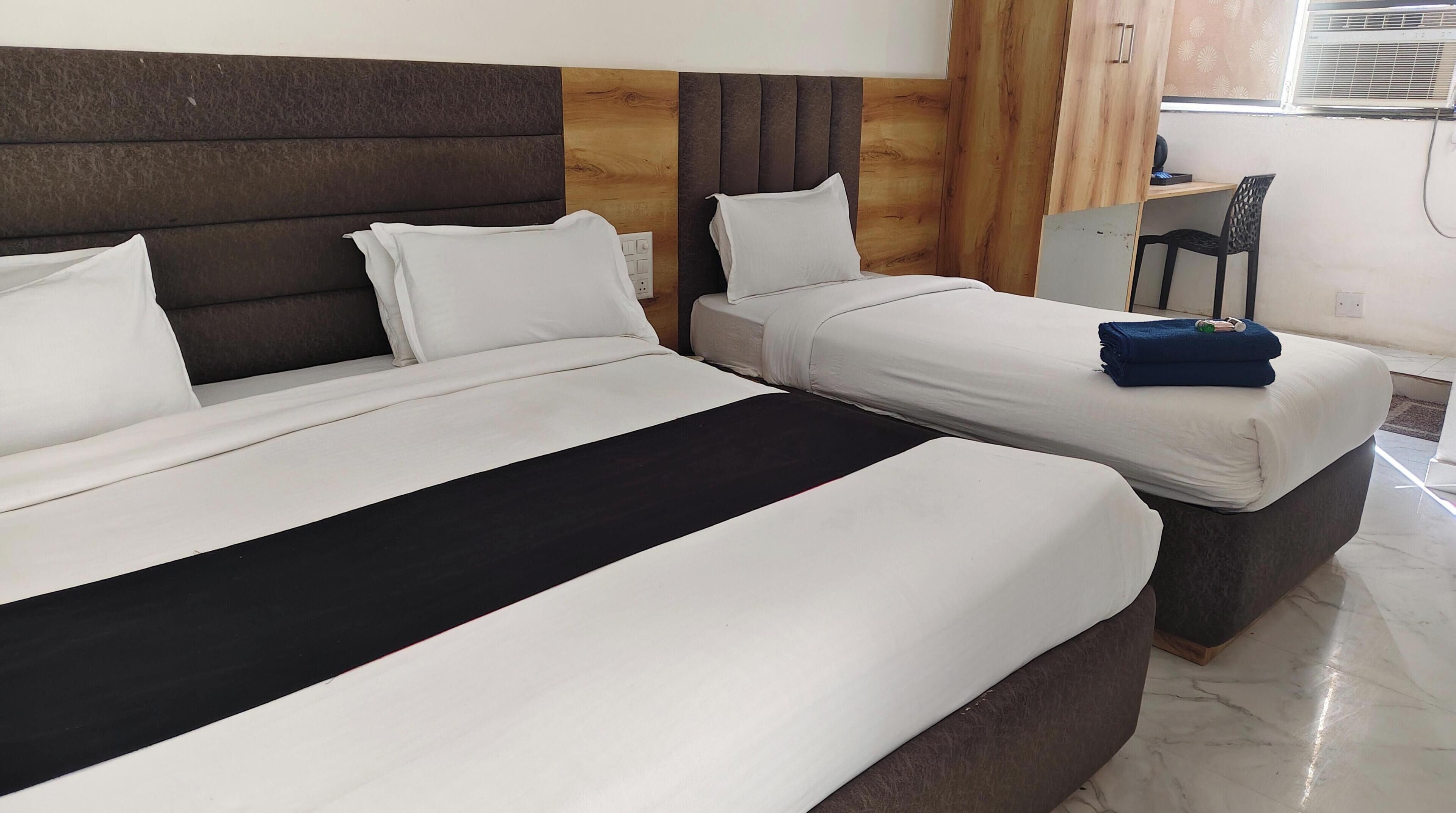 Een hotelkamer met twee bedden, een houten hoofdbord, een bureau en een stoel.