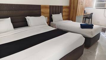 A hotel room with two beds, a wooden headboard, a desk, and a chair.