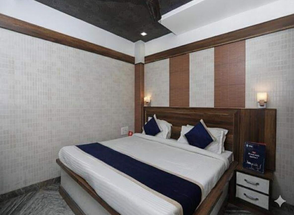 Une chambre d’hôtel avec un grand lit, une tête de lit en bois, deux tables de chevet et une petite table de nuit.