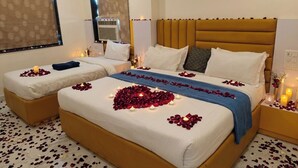 Ein Doppelbett mit Rosenblättern und Kerzen, ein Nachttisch und ein Kopfteil.