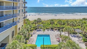 A hotel with a pool, beach view, and outdoor seating area. - Ocean View Resort Condo w Private Master Suite (Myrtle Beach)