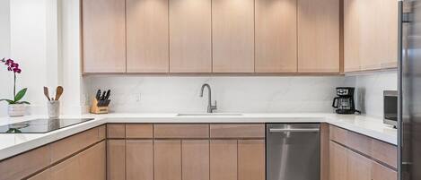 A modern kitchen with wooden cabinets, a stainless steel dishwasher, and a white countertop.