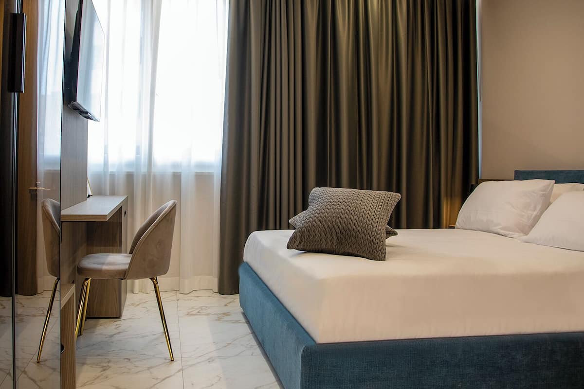 Una habitación de hotel con cama, escritorio, silla y televisor.
