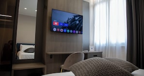 Ett modernt hotellrum med en stor platt-TV som är monterad på väggen och som visar en startsida med olika appikoner.