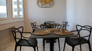 A dining area with a table set for four, black chairs, and a world map wall decoration. - Maison D'élite (Naples)