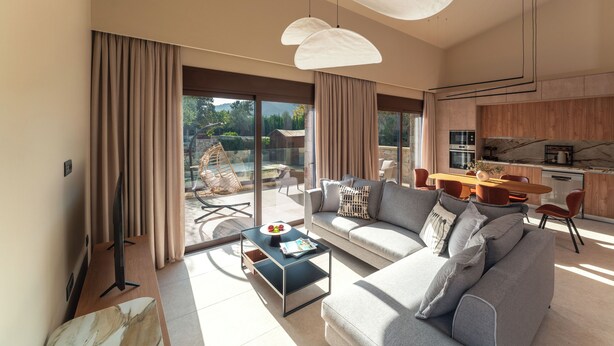 Ein modernes Wohnzimmer mit Sofa, Couchtisch und einem Essbereich mit Stühlen.