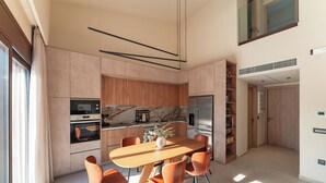 Eine moderne Küche mit Marmor-Spritzschutz, Holdekor-Schränken und einem Essbereich mit Holztisch und orangefarbenen Stühlen.