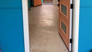 Un pasillo con puerta de madera, pared azul y una lámpara en el techo.