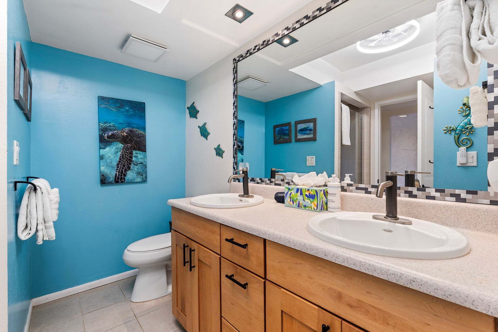 Een badkamer met twee wastafels, een toilet, een spiegel en een plafondlamp.