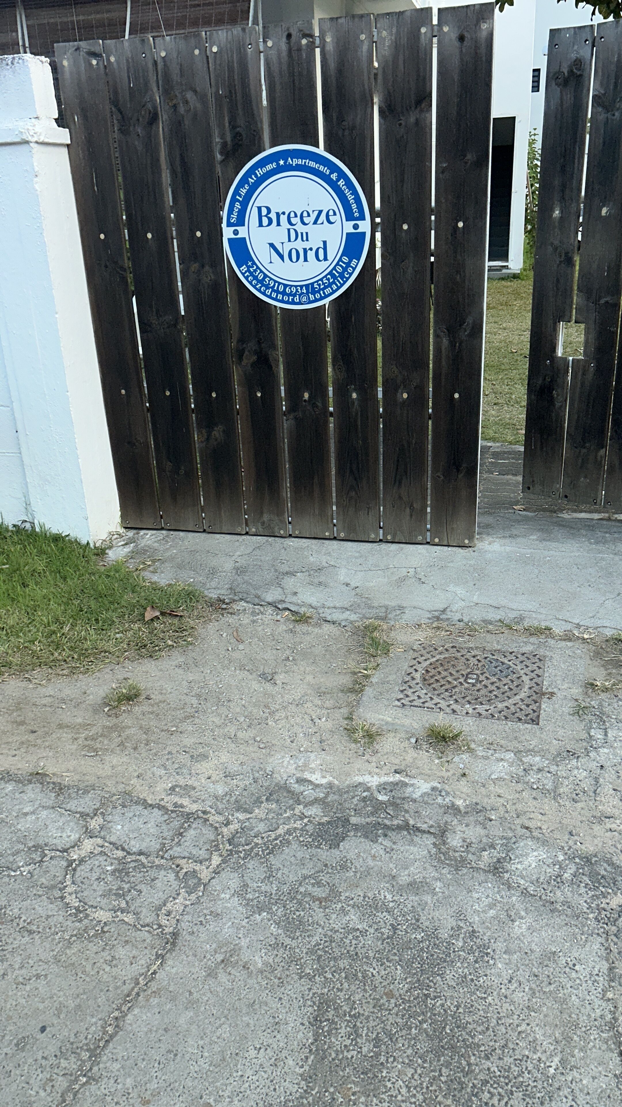 Une porte en bois sur laquelle est apposée une plaque indiquant « Breeze du Nord » et mentionnant les coordonnées.