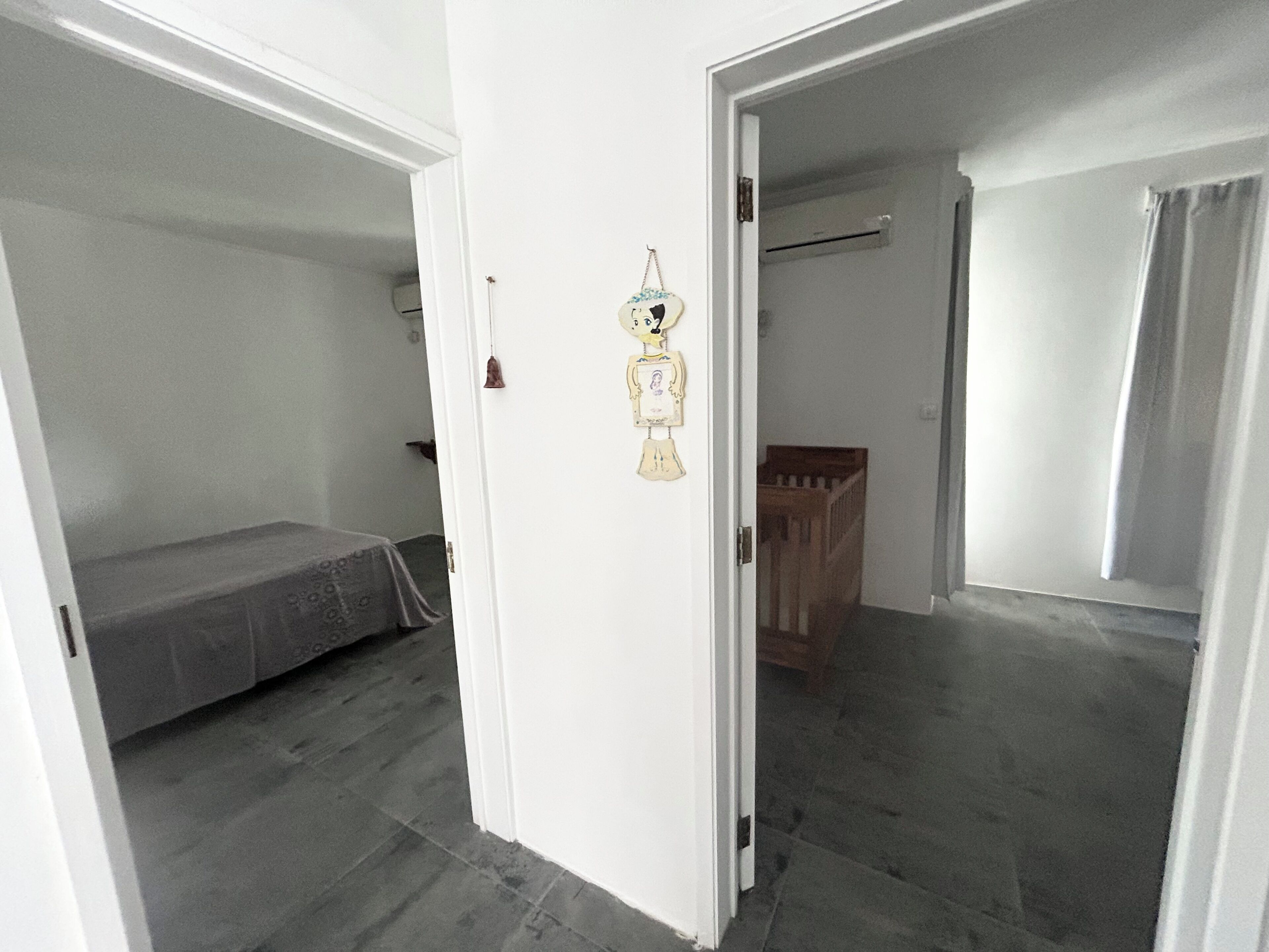 Een kamer met een bed, een ledikant en een deur naar een andere kamer.
