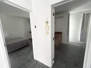 A room with a bed, a crib, and a door leading to another room. - Breeze du nord (Grand-Baie)