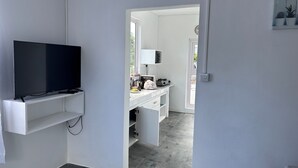 Eine moderne Küche mit integriertem Fernseher, weißen Schränken und einer Nespresso-Maschine.