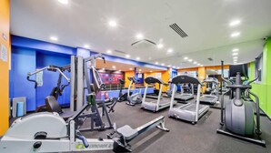 Et fitnesscenter med forskellig træningsudstyr, herunder løbebånd, crosstrainere og styrkemaskiner.