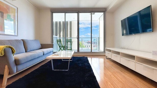 En moderne stue med sofa, sofabord og fjernsyn.