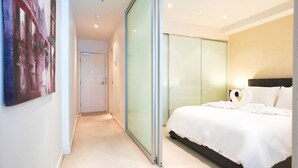 A modern hotel room with a large bed, a glass partition, and a painting on the wall. - Resort-Style 1BR Apt in Adelaide CBD | Pool & Spa (Adelaide)