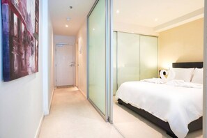 Ein modernes Hotelzimmer mit einem großen Bett, einer Glastrennwand und einem Gemälde an der Wand.