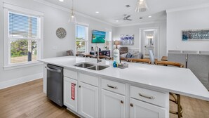 Een moderne keuken met witte kasten, een groot eiland en een vaatwasser.