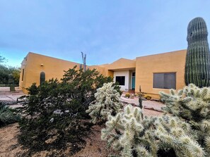 A desert-style building with a yellow facade, arid landscaping, and a prominent cactus in the foreground. - Authentic Desert Vibes 3-bedroom house with pool & AC in charming Cave Creek (Cave Creek)